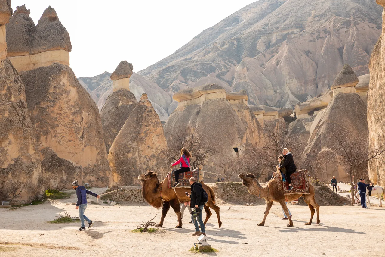 Tourists enjoying a camel ride in Cappadocia, Turkey – scenic valleys and unique rock formations